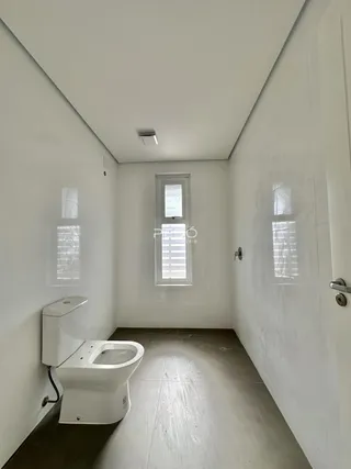 Foto de um banheiro estreito e branco com piso de concreto.