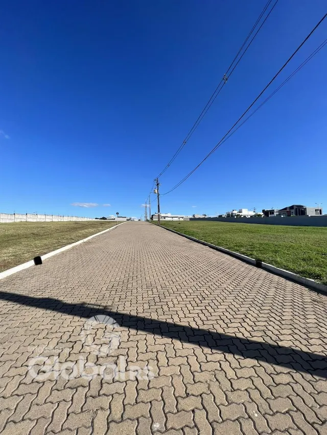 Vista externa de um caminho pavimentado que leva a uma área gramada.