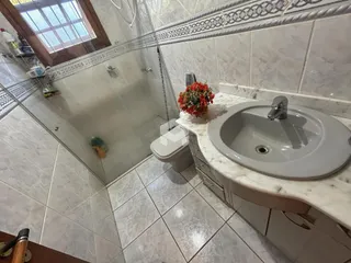 Banheiro com box de vidro e bancada de mármore.