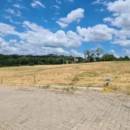 Vista externa de um campo aberto com vegetação seca e uma estrada no primeiro plano.