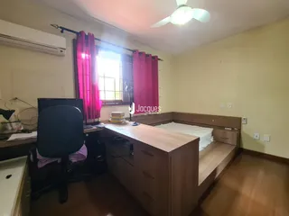 Quarto com janela e cabeceira de madeira em um imóvel no Brasil.