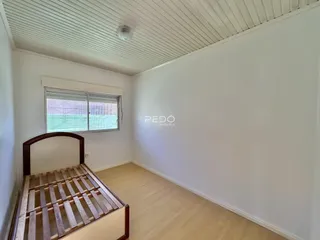 Quarto com janela e piso de madeira clara.