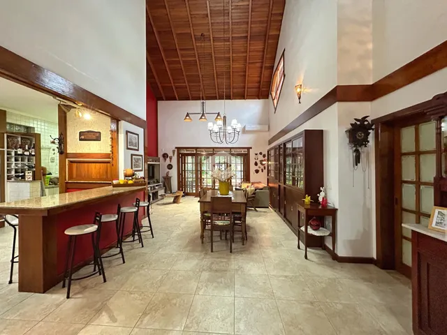 Interior de uma sala de jantar ampla com pé direito alto e forro de madeira.