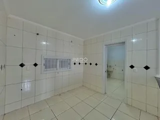 Um corredor com paredes brancas e piso de cerâmica.