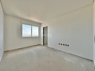 Interior de um cômodo vazio com paredes brancas e piso de concreto.