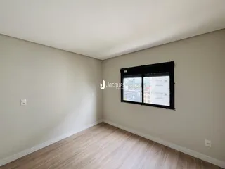 Quarto com piso de madeira clara e janela grande.
