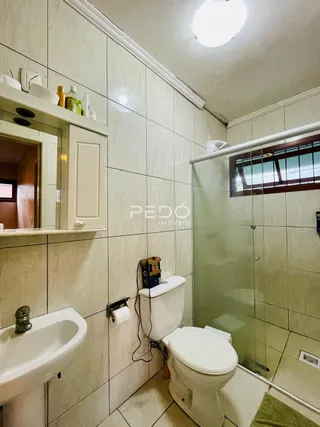 Banheiro com piso de cerâmica e box de vidro.