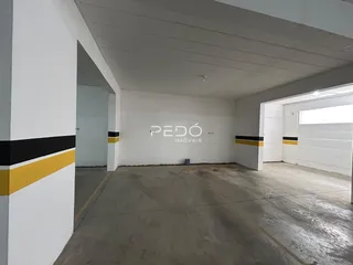 Espaço interno com paredes brancas e piso de concreto.