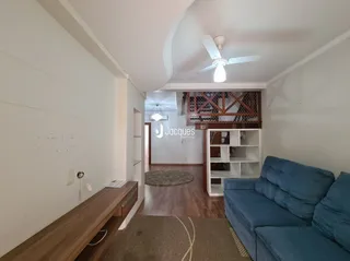 Ambiente interno de uma sala com piso de madeira e paredes brancas.