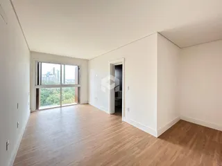 Ambiente interno com piso de madeira clara e grande janela.