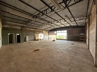 Espaço industrial amplo com teto metálico exposto e piso de concreto.