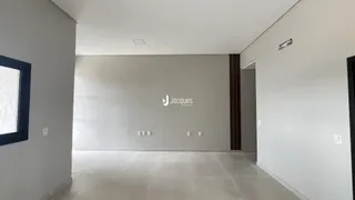 Interior de um espaço vazio com paredes brancas e piso claro.