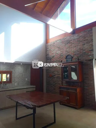 Foto de um ambiente interno com mesa de madeira e parede de tijolos aparentes.