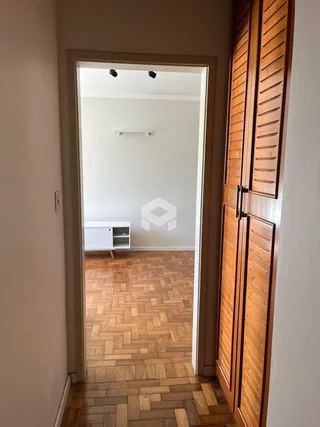 Hall de entrada com piso de madeira e portas de madeira no interior de uma residência.