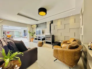 Sala de estar moderna com sofá e poltronas de couro em um ambiente claro.