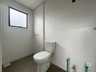 Foto interna de um banheiro com paredes brancas e piso de concreto.