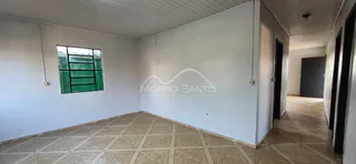 Corredor interno com piso de ladrilho claro e paredes brancas.