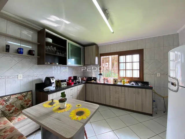Vista da cozinha e sala de jantar com armários de madeira e piso cerâmico.