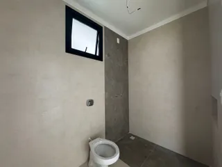 Foto de um banheiro com piso de cerâmica e vaso sanitário branco.