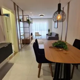 Mesa de madeira escura com cadeiras em um ambiente interno claro.