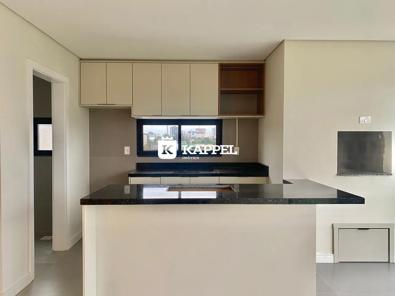 Vista da cozinha com armários superiores e bancada escura em um imóvel em Lajeado.