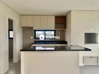 Vista da cozinha com armários superiores e bancada escura em um imóvel em Lajeado.