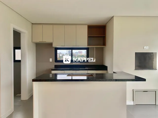 Vista da cozinha com armários superiores e bancada escura em um imóvel em Lajeado.