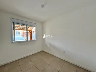 Ambiente interno de uma sala com piso de cerâmica e janela.