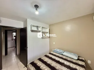 Quarto com cama e prateleiras brancas na sala.