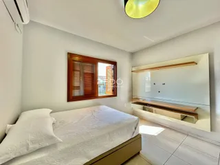 Quarto com cama e janela de madeira no interior da residência.