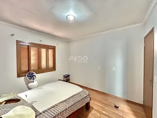 Foto de um quarto com cama e janela de madeira em uma residência.