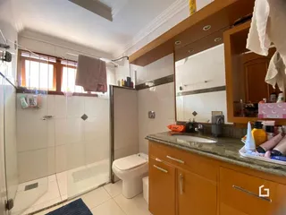 Banheiro com revestimento cerâmico e piso branco.