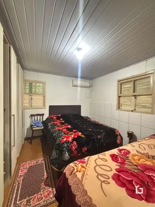 Quarto com cama e janelas em uma residência.