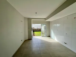 Corredor interno com piso de cerâmica e porta de vidro que dá acesso ao jardim.