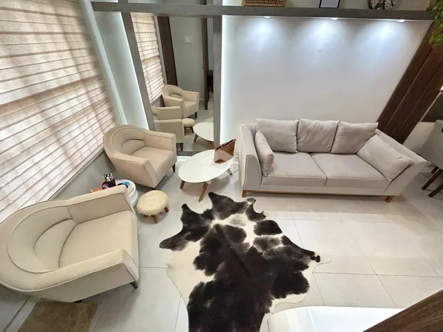 Sala de estar com sofás e poltronas claras em um imóvel no Brasil.