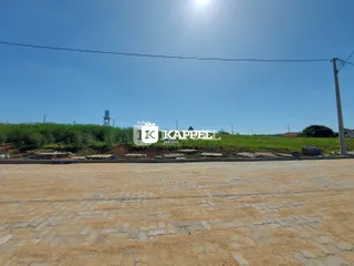 Vista externa de um terreno com vegetação e pavimento sob luz solar intensa.