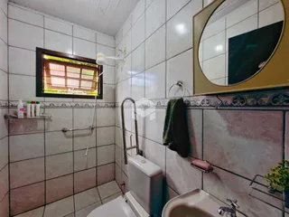 Foto de um banheiro com azulejos brancos e detalhes em tons de rosa e marrom.