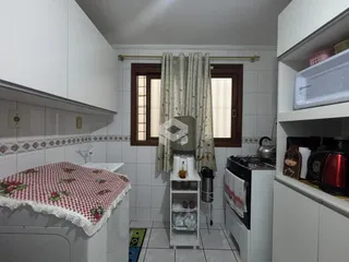 Interior de uma cozinha com azulejos brancos e armários.