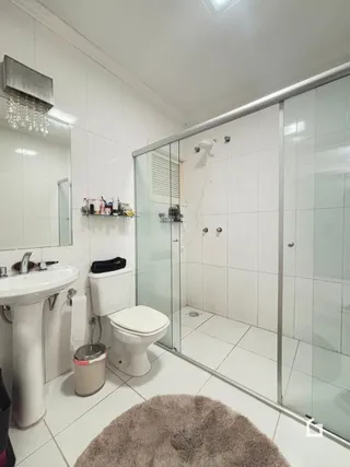 Banheiro com revestimento cerâmico branco nas paredes.