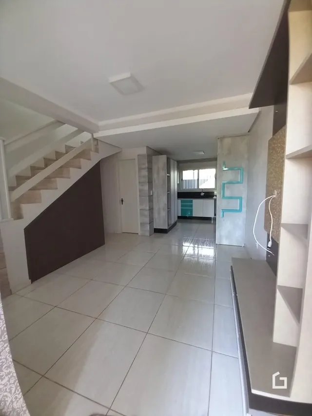 Vista de um corredor interno com escadaria e piso de cerâmica.