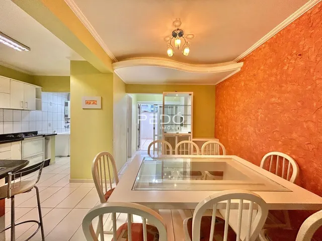Uma sala de jantar com mesa e cadeiras brancas em um apartamento.