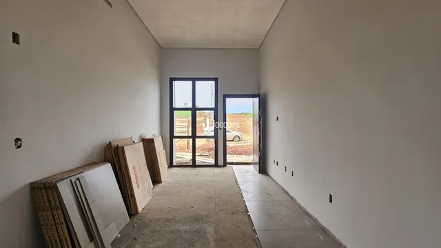 Interior de um ambiente com paredes brancas e piso de concreto.
