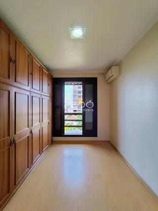 Foto de um corredor interno com armários de madeira e piso claro.