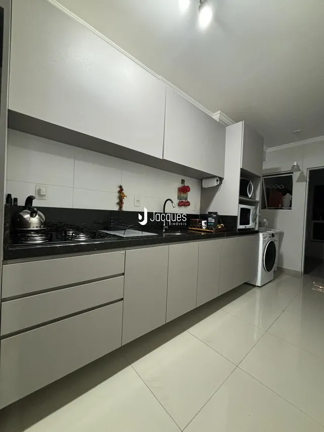 Cozinha moderna com armários brancos e bancada escura.