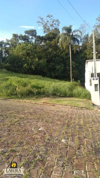 A vista externa da propriedade mostra um terreno gramado e pavimentação de paralelepípedos.