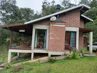 Fachada de uma casa de tijolos com varanda e jardim.