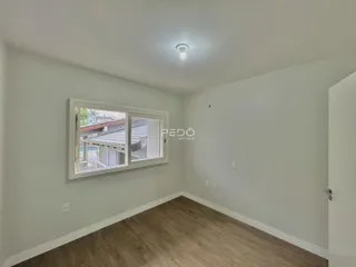 Sala de estar com piso de madeira clara e paredes brancas.