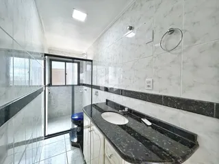 Interior de um banheiro com revestimento de azulejos brancos e bancada escura.