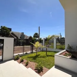 Vista externa mostrando um jardim gramado e uma área de piso de concreto.