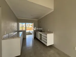 Vista interna de uma cozinha com armários brancos e piso de cerâmica.
